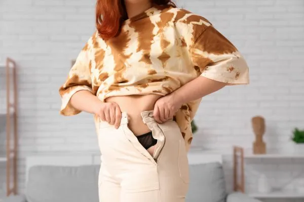 Image of woman trying to do her trousers up after pregnancy weight gain Lancashire