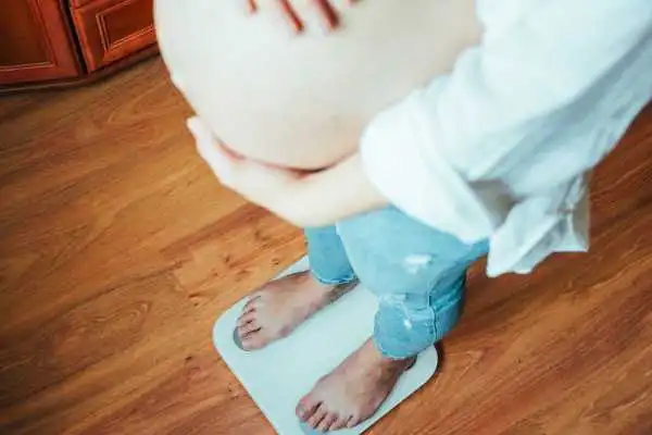 Image of woman weighing herself and experiencing weight gain through pregnancy Lancashire